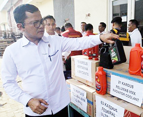 Direskrimsus Polda Sumut Kombes Pol Teddy Jhon S Marbun (kiri) mengambil barang bukti saat rilis pengungkapan produsen oli palsu di Percut Seituan, Deliserdang, Senin (28/8/2023). /Foto Trib

